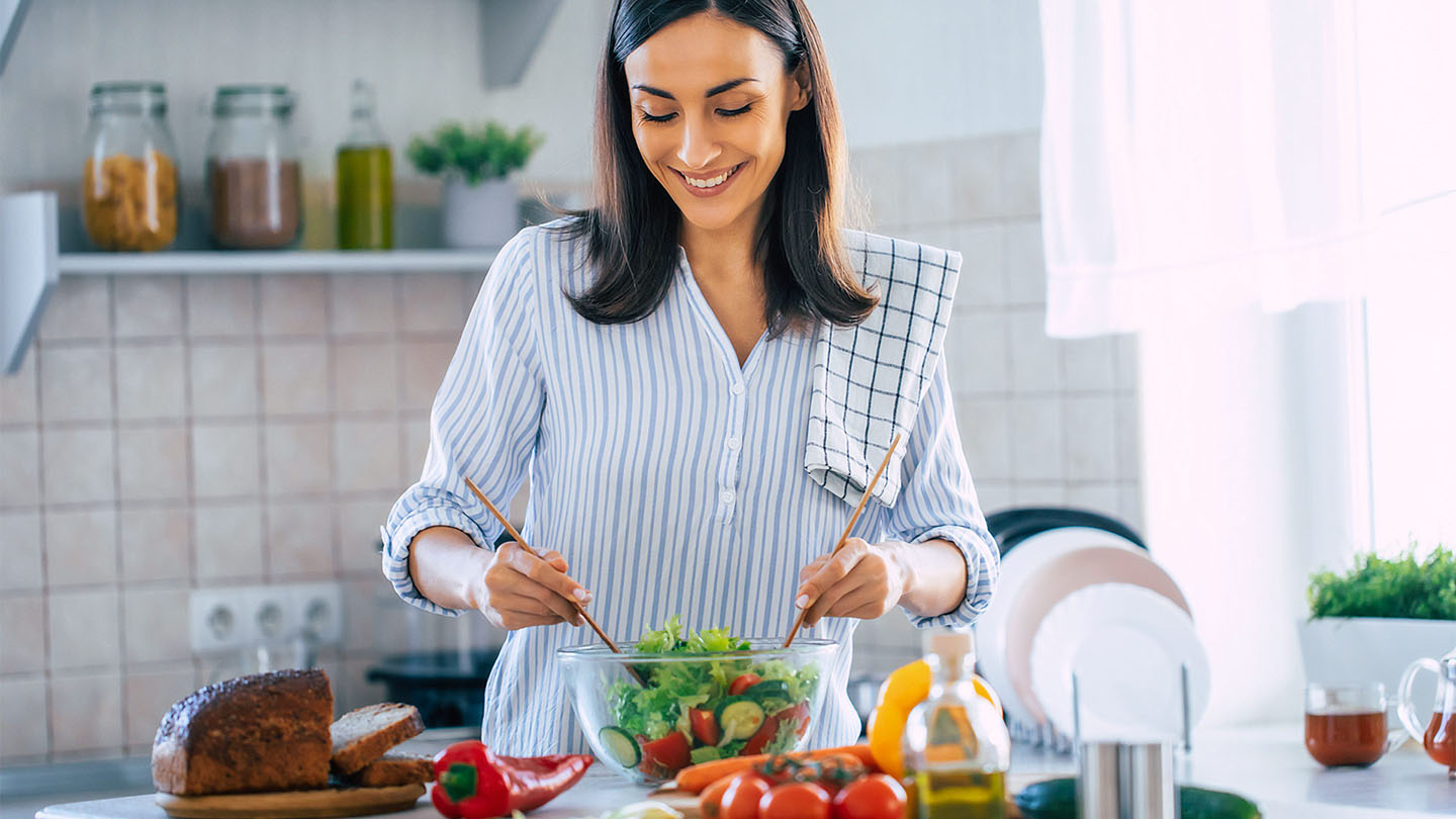 Jauna sieviete gatavo veselīgu maltīti.