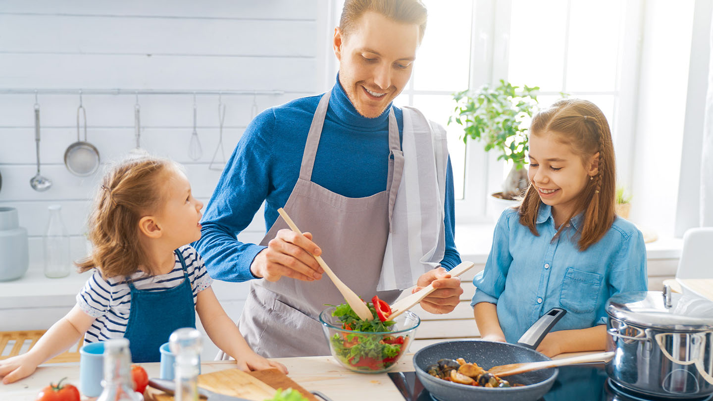 Ģimene virtuvē gatavo veselīgu maltīti.