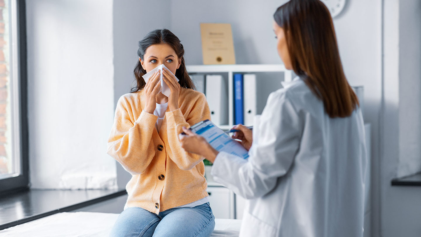 Sieviete ar gripu tiek pārbaudīta pie ārsta.