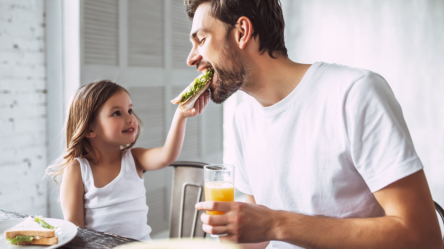 Tēvs un bērns bauda sviestmaizi.