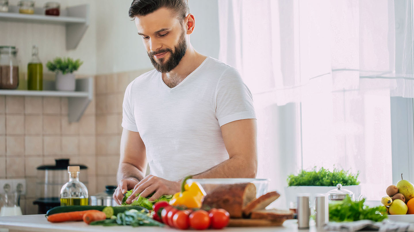 Vīrietis sportists virtuvē gatavo veselīgu maltīti.