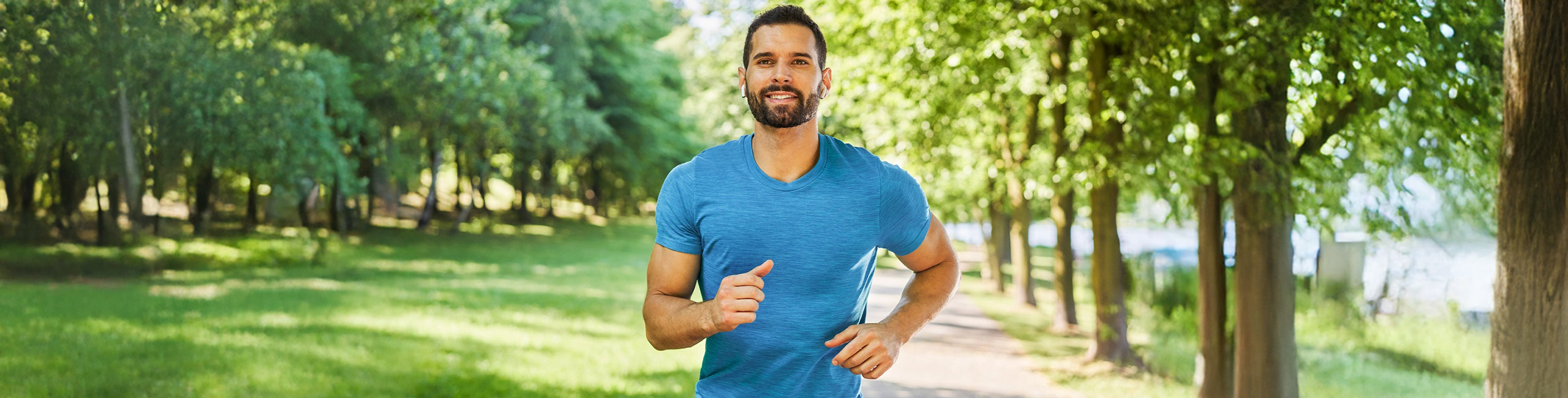 Vīrietis skrien parkā, fiziska aktivitāte.